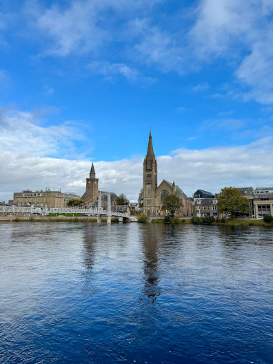 Photograph of Inverness from across the river with reflections of buildings in the water